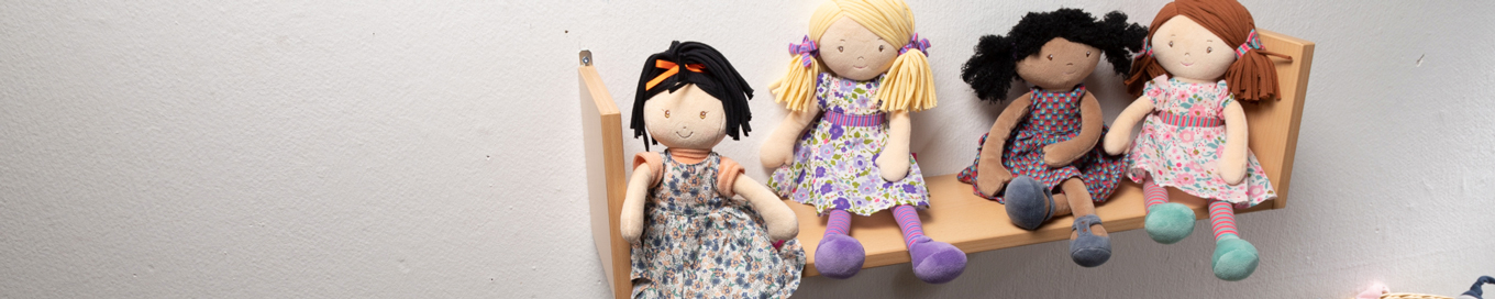 Vier Puppen sitzen auf einem Wandregal