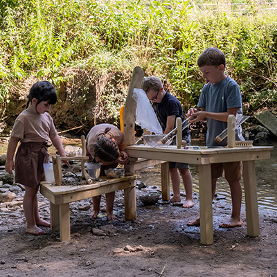 4 Kinder spielen mit Sand und Wasser am Fluss mit der Kalalier Entdeckerstation