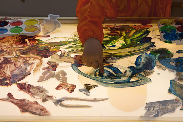 Experimentierwanne Kind malt mit dem Finger in der Experimentierwanne