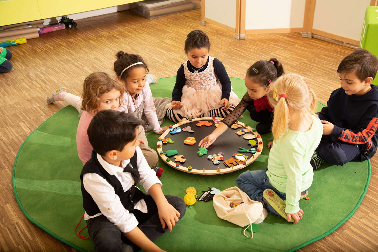 Kinder sitzen spielend im Kreis