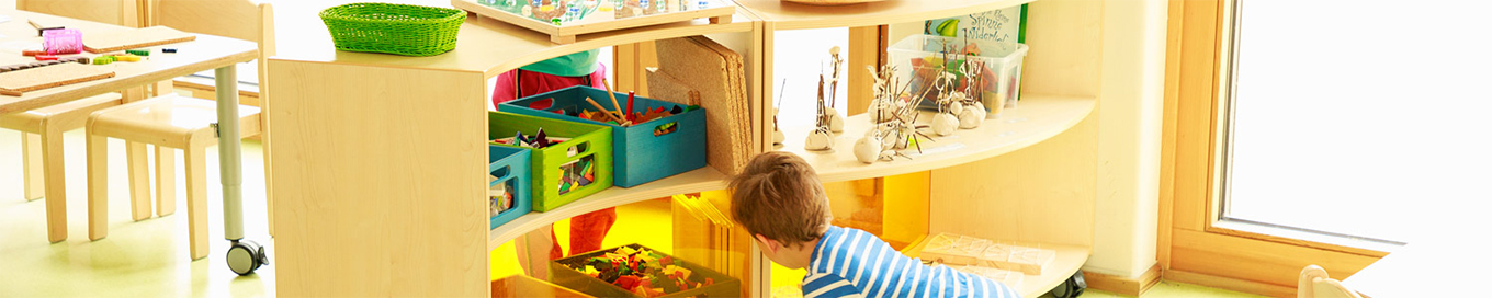 Bogenregal mit Aufbewahrungsboxen aus dem sich ein Kind Spielsachen nimmt