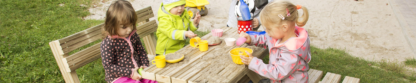 Kinder sitzen gemeinsam im Garten auf Bänken