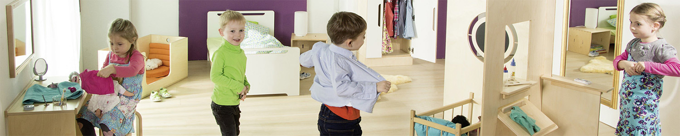 Eingerichteter Rollenspielraum mit Puppenbett, Schminkecke und Kleiderschrank, in dem Kinder spielen