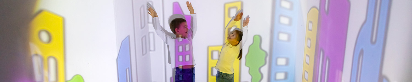 Kinder spielen in bunten an die Wand projizierten Lichtflächen