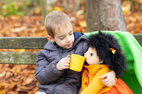 JOYK Emelie Kind reicht einer JOYK Puppe Tee