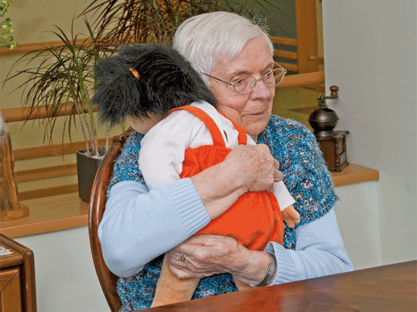 Seniorin umarmt die Empathiepuppe Emelie