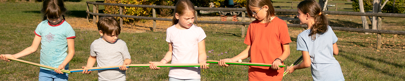 Fünf Kinder bilden mit der Rinnenrallye eine Schlange und lassen einen Ball dort entlang rollen