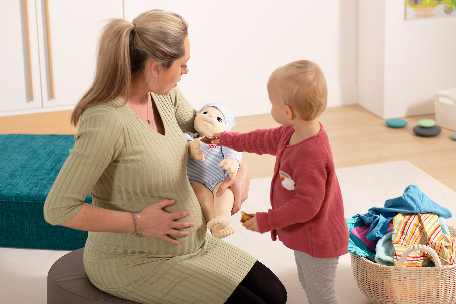Schwangere Mutter mit Kind und Neugeborenen Empathiepuppe