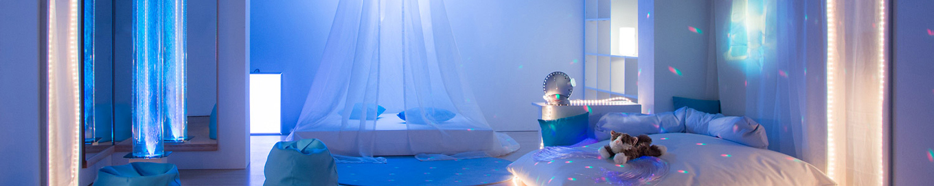 Eingerichteter Sinnesraum mit Matratze, Baldachin, Wassersäule, Sitzsäcken und angenehmen, blauen Stimmungslicht