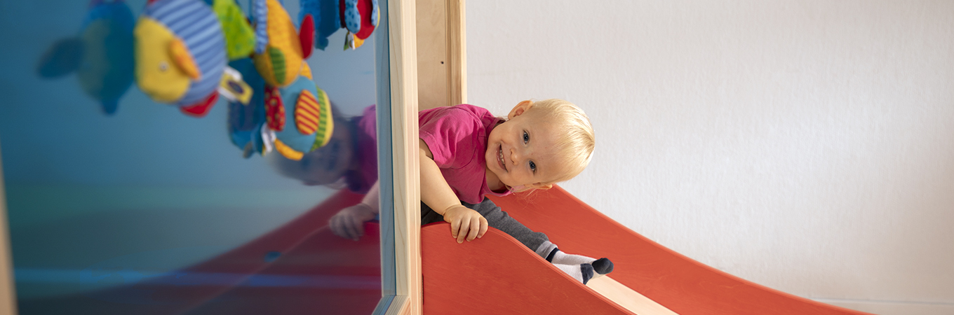 Kind rutscht im Kindergarten auf einer Rutsche herunter