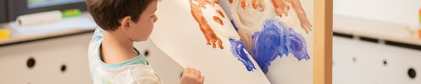 Kind erstellt einen Abdruck von einem frisch gemalten Proträt