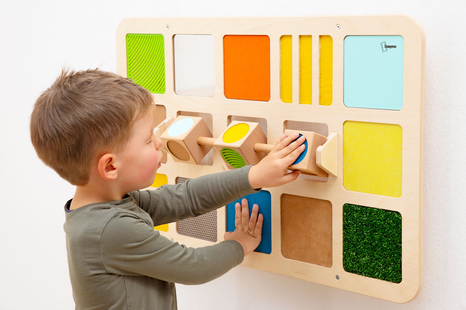 Kind ertastet Materialien am Wandspiel Tastwürfel