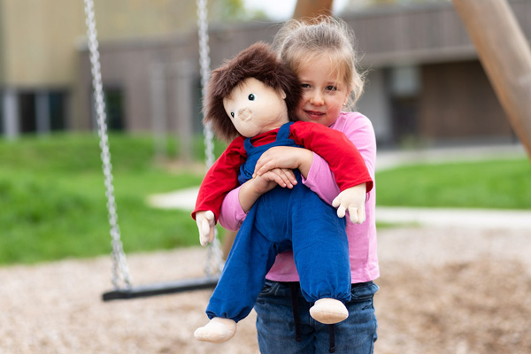 Kind hält JOYK Puppe im Arm