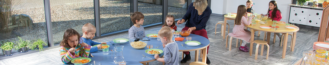 Eine Tafel aus Doki-Tischen an denen eine Gruppe Kinder isst